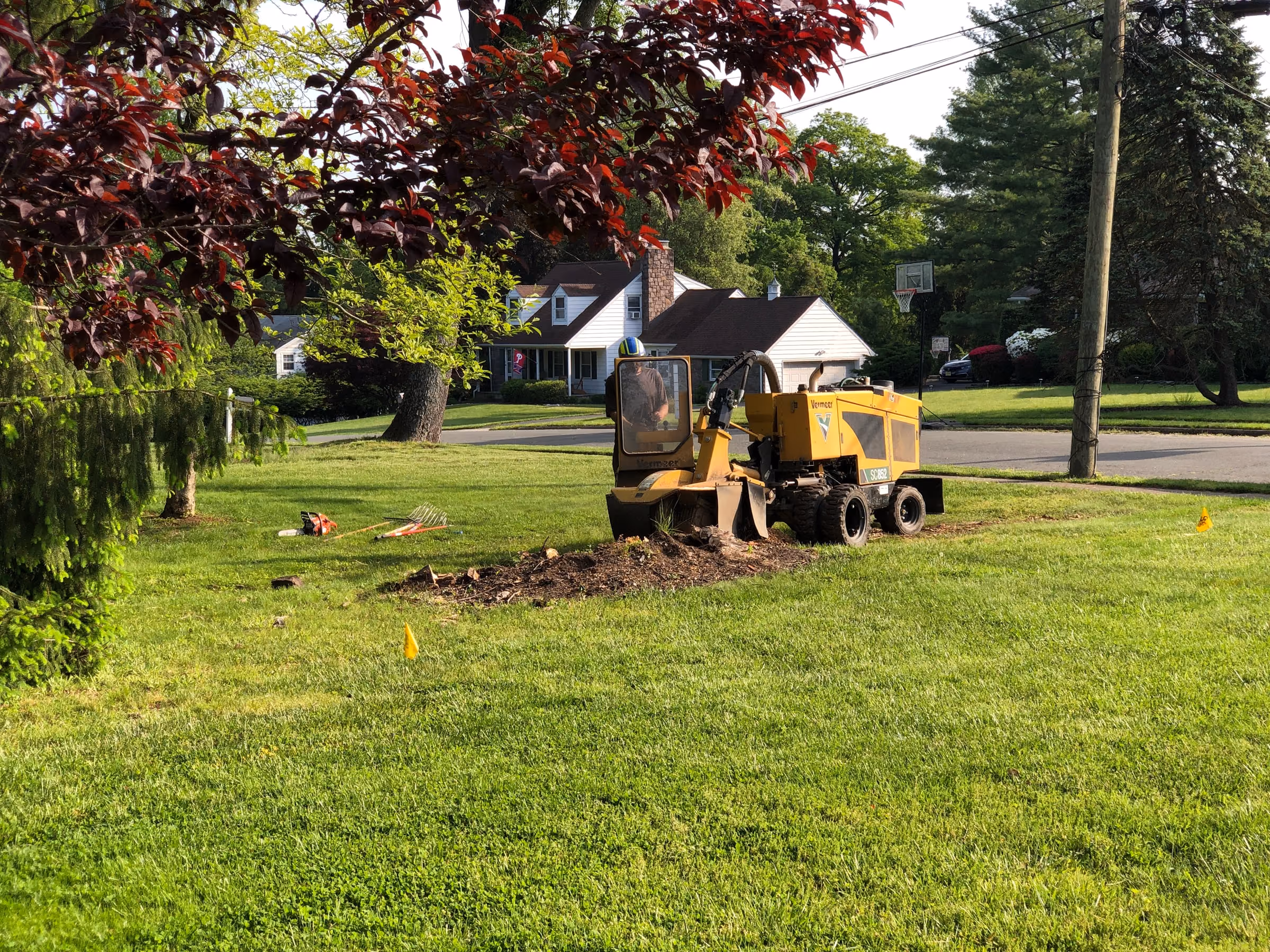 A stump grinder working on a stump in a grassy yard